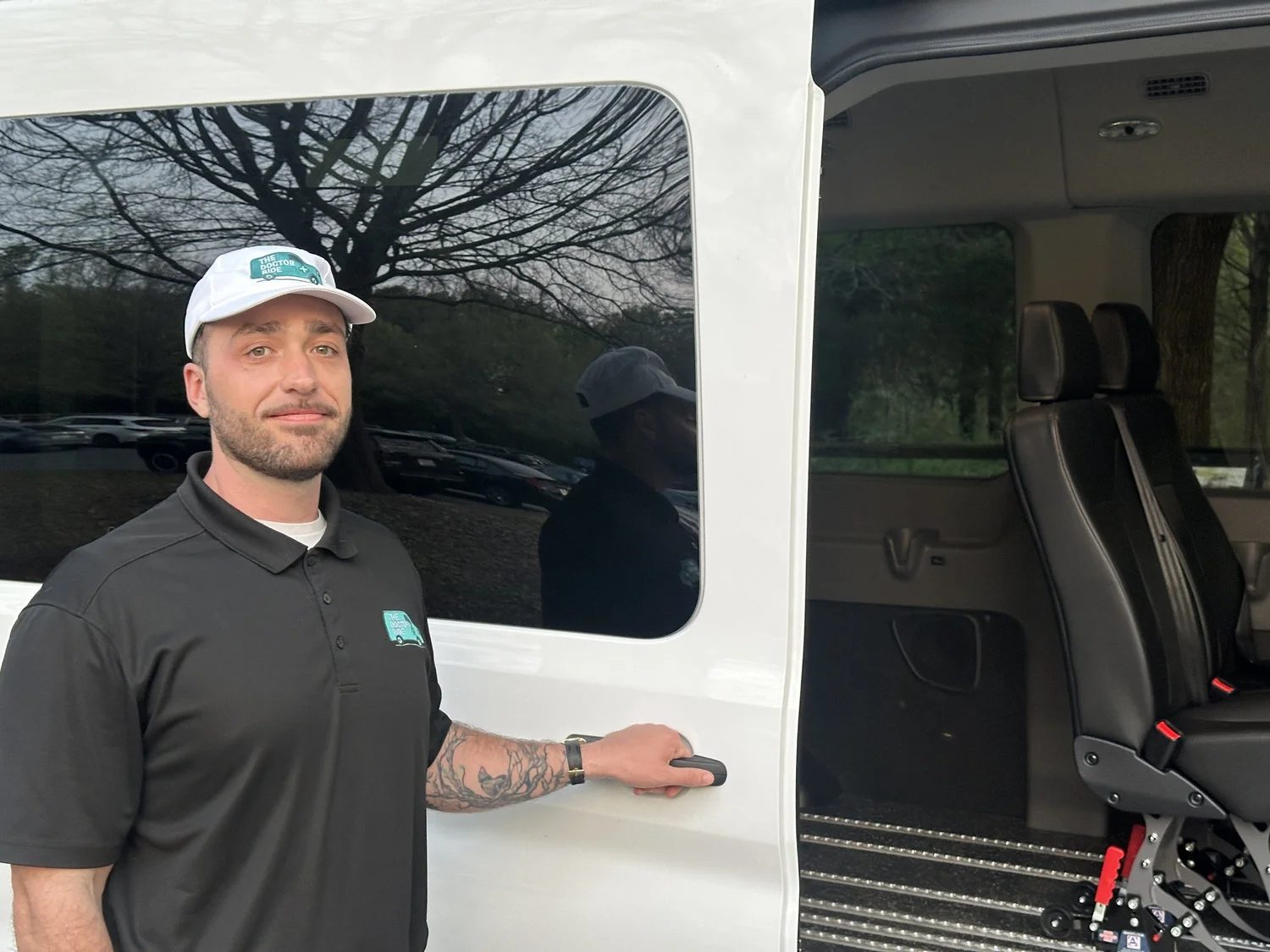 Mac Andrews at the door of a Doctor Ride NEMT van in his Doctor Ride cap and polo